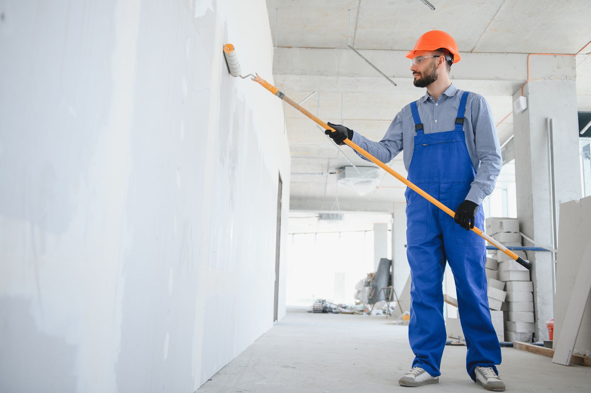 Painter man painting the wall with a paint roller.