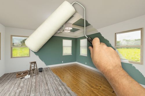 A man using a paint roller to reveal a room with fresh paint.