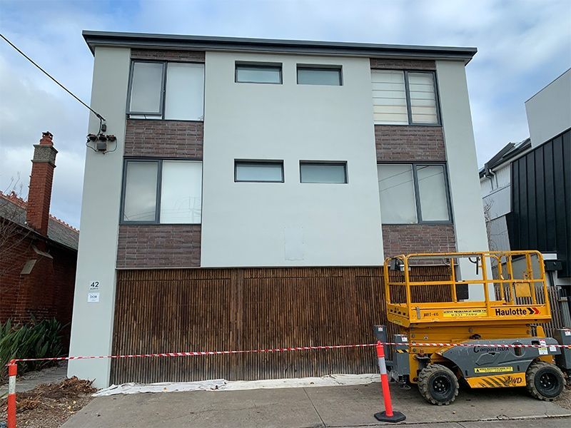 A large building with a yellow scissor lift parked in front of it.