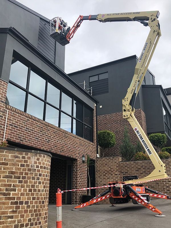 A crane is sitting in front of a brick building.