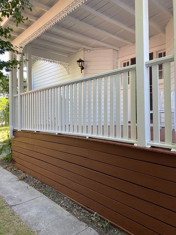A porch with a white railing and a brown wall