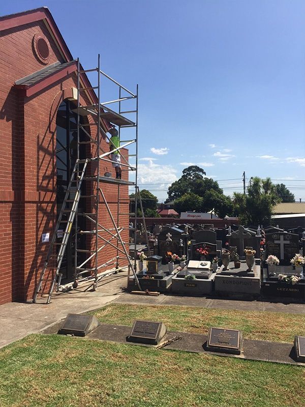 A cemetery with a brick building and scaffolding in front of it.