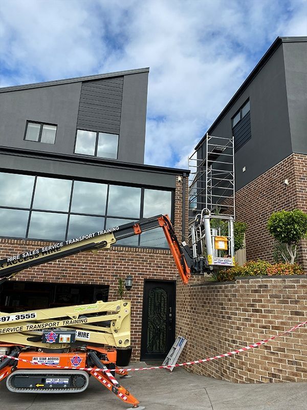 A crane is sitting in front of a brick building.