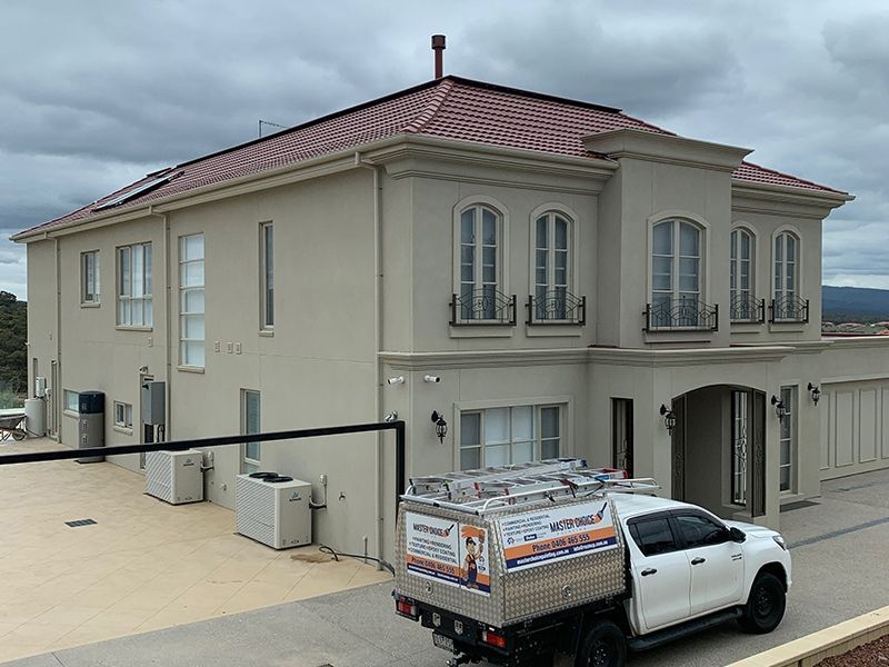 A white truck is parked in front of a large house.