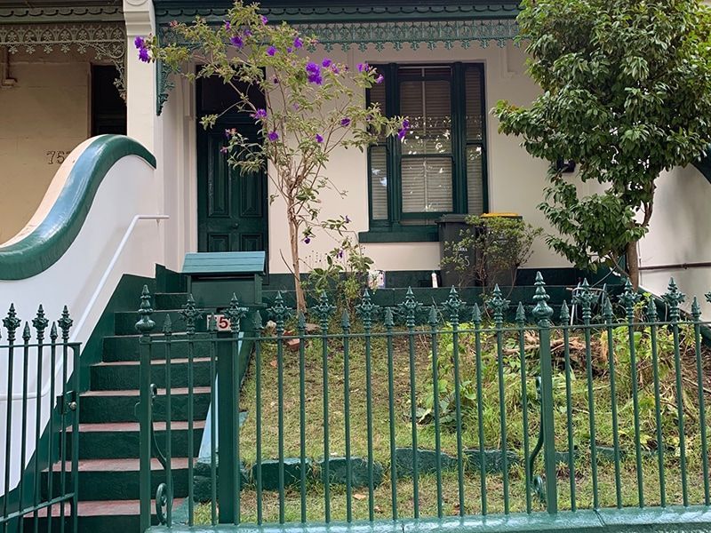A porch with a white railing and a brown wall