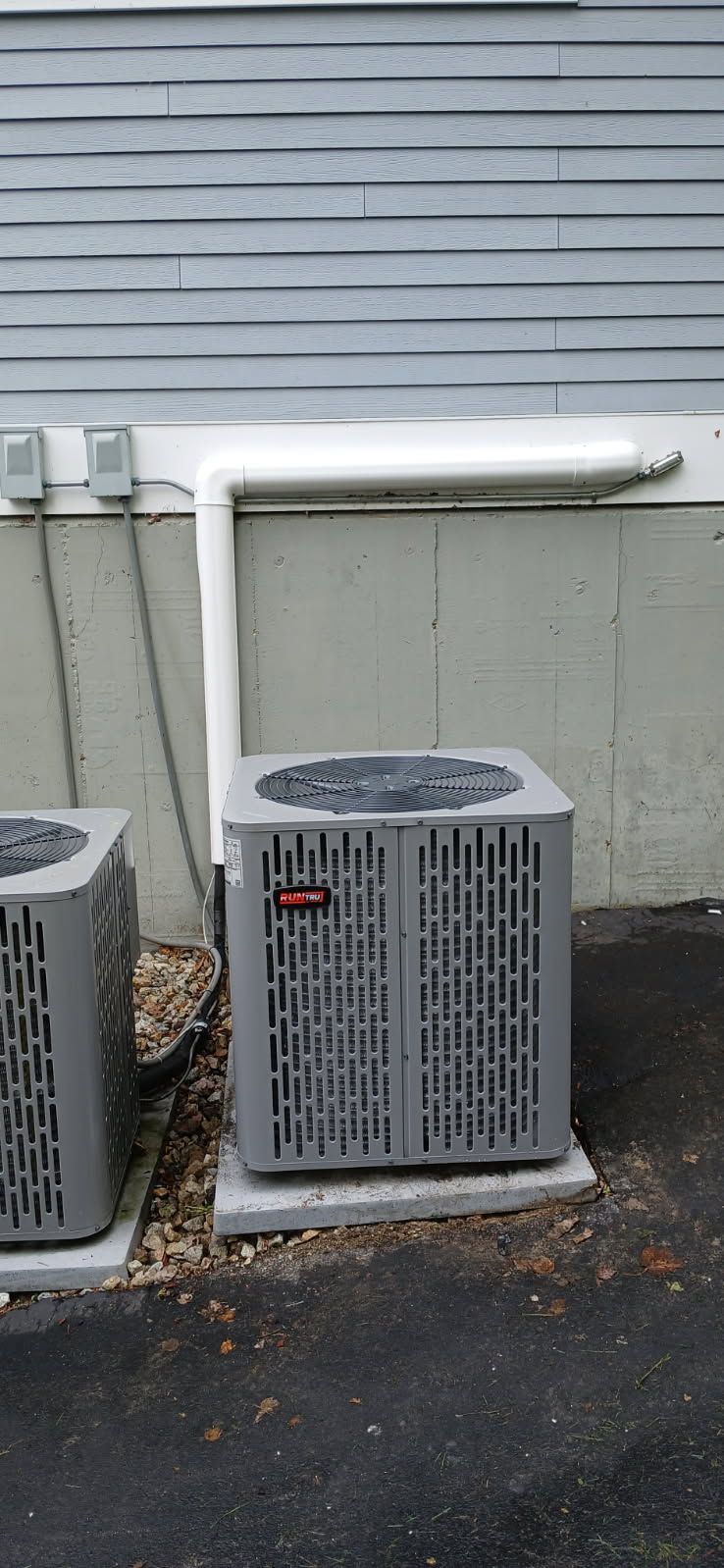 Air conditioning unit covered in ice; exterior wall with a white pipe covered in ice running from it.