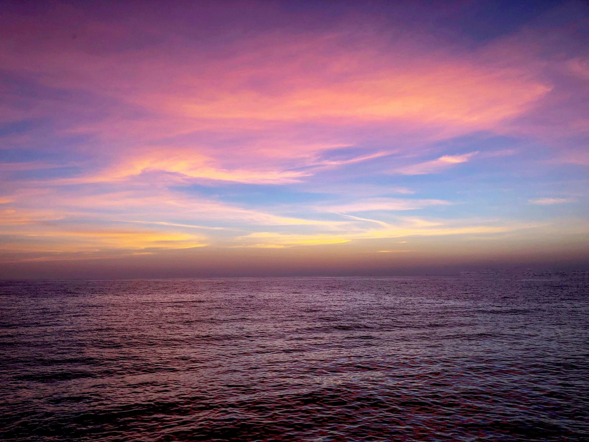 A sunset over the ocean with a purple sky