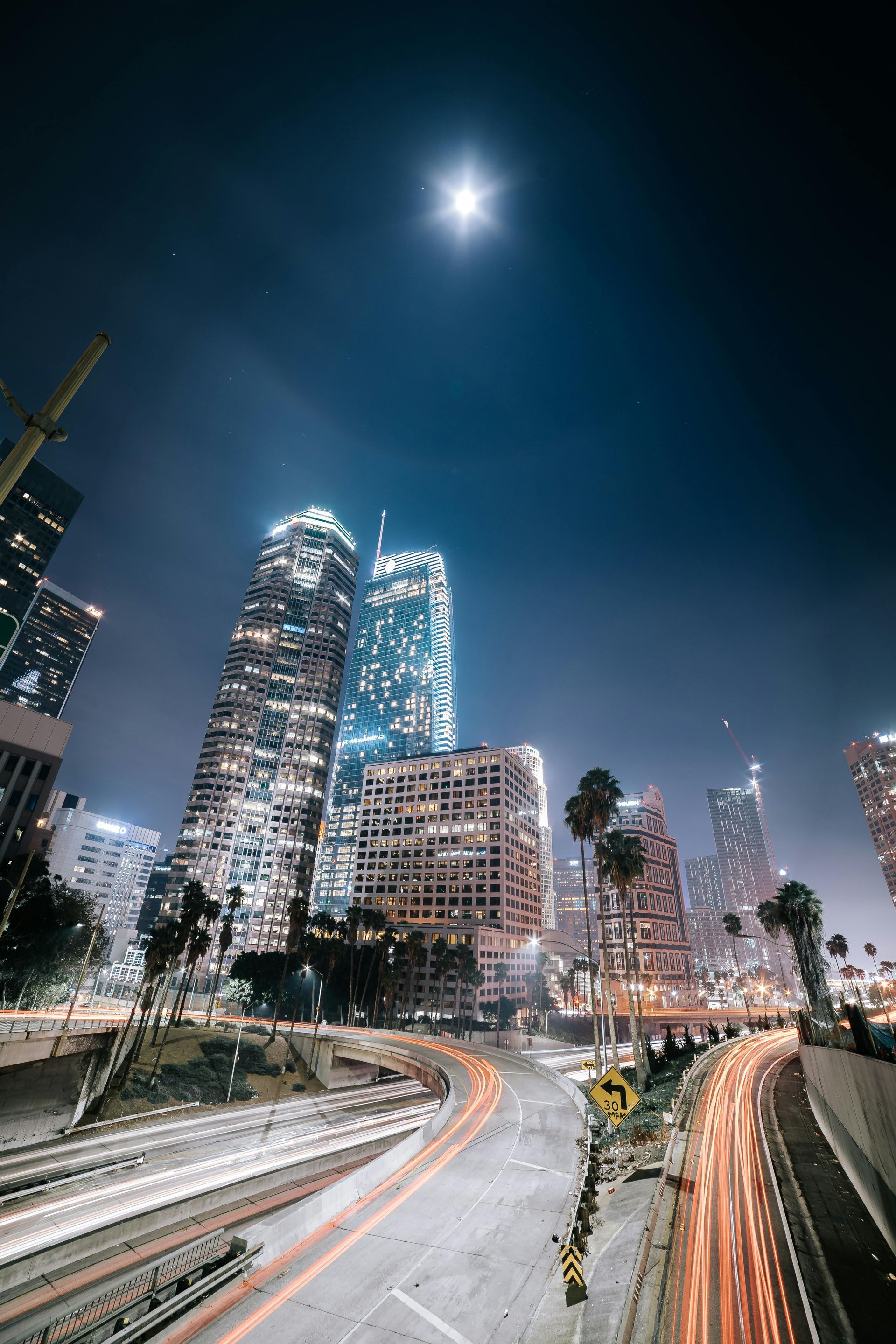 A long exposure photo of a city at night with a full moon in the sky.