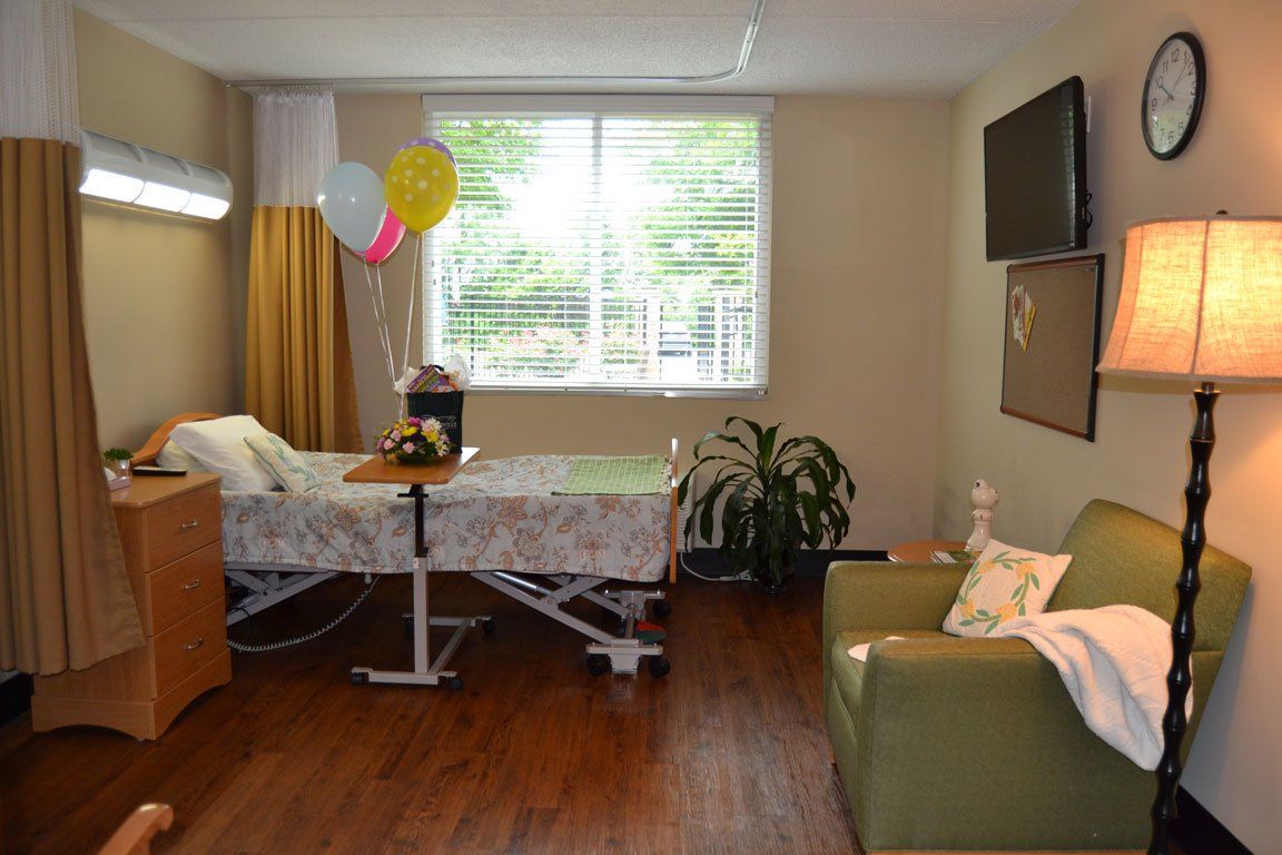 A hospital room with a bed , chair , lamp and television.