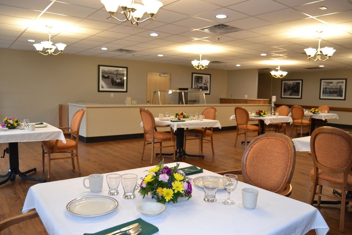 A dining room with tables and chairs and flowers on them