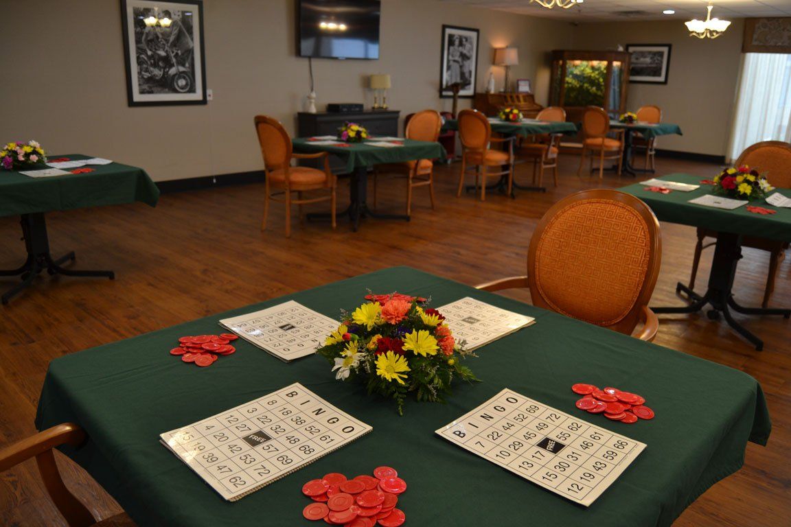 A room with tables and chairs and a table with a flower arrangement on it.