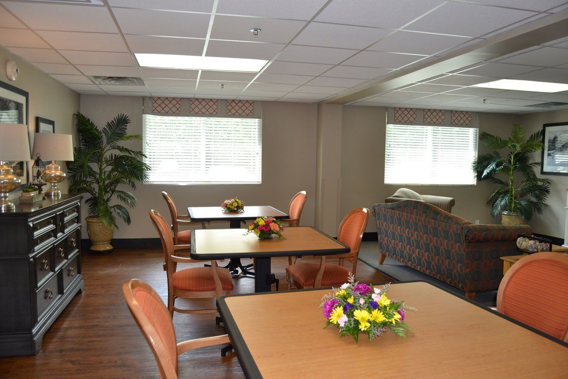 A living room with tables and chairs and a vase of flowers on the table.
