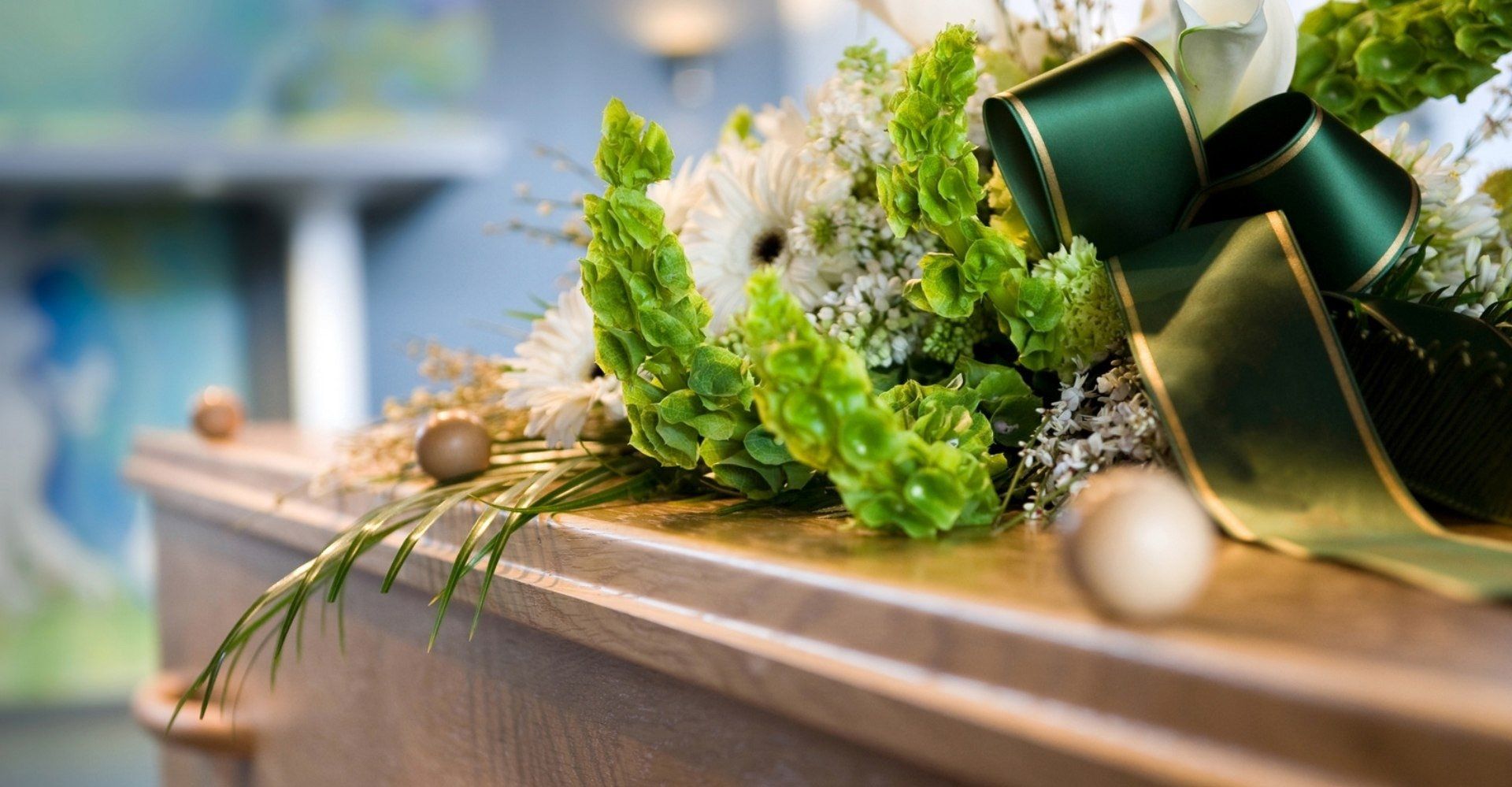 Fiori con nastro verde su una bara. Un'ambientazione funebre con colori tenui.
