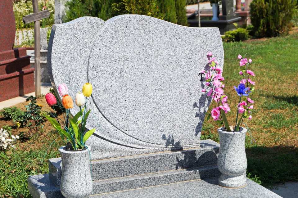 lapide in granito con vasi e omaggi floreali