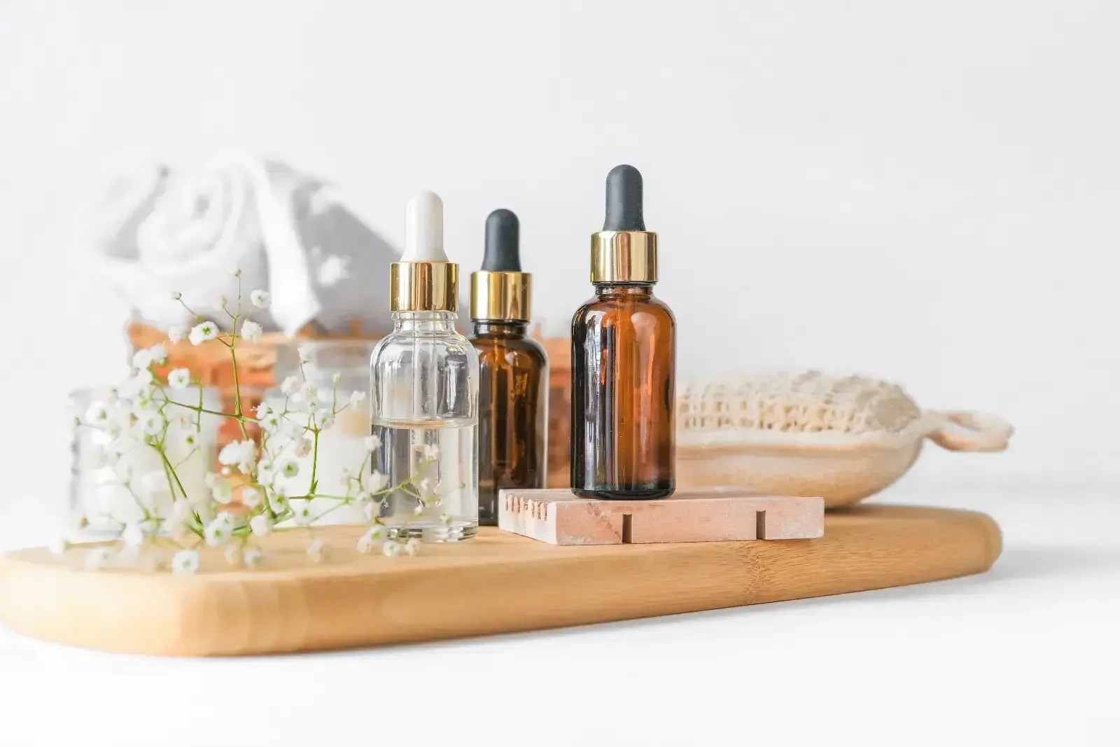 Spa bottles and dried flowers on a wooden tray in a bright, minimalist setting