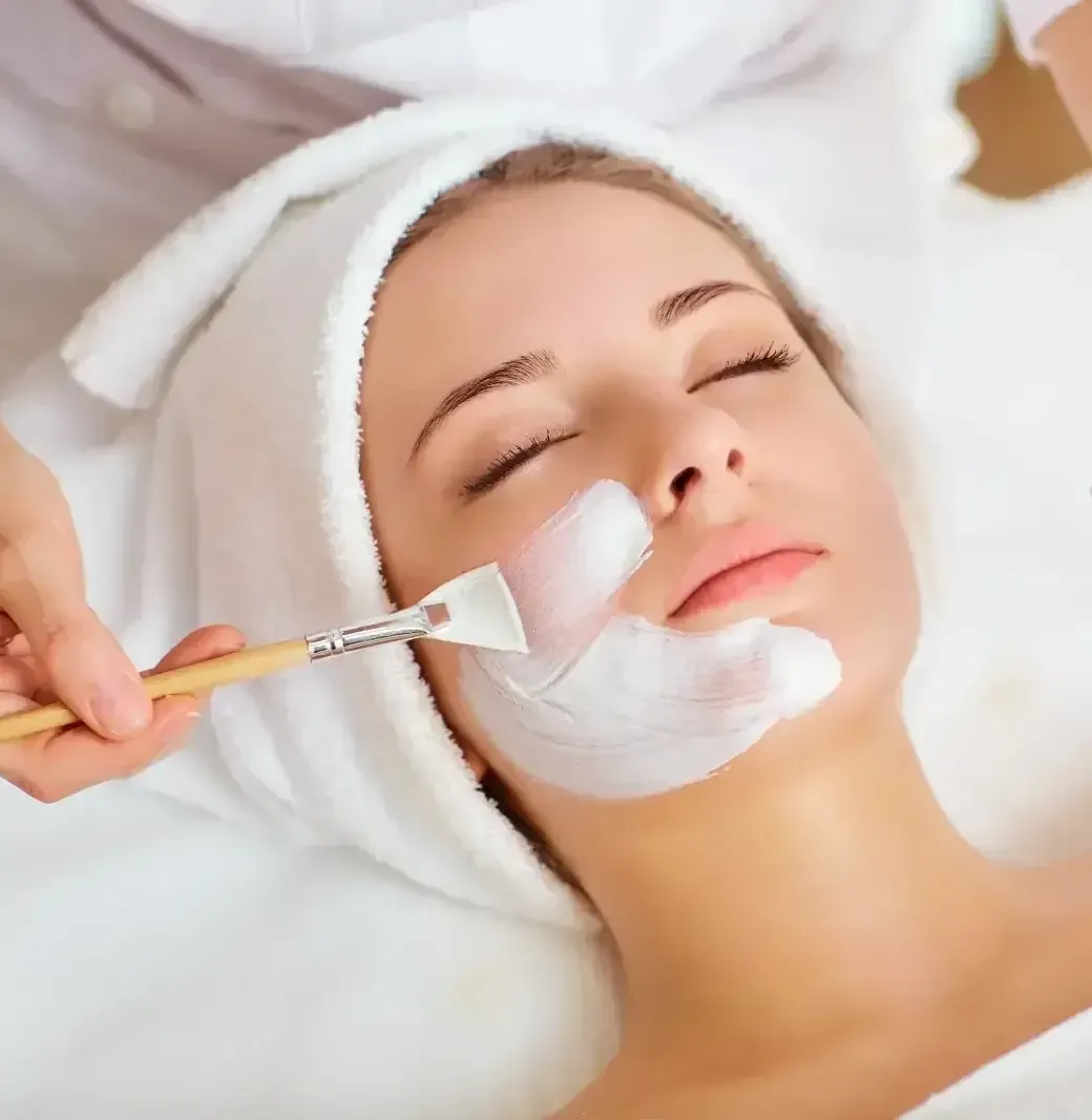 Spa facial treatment with white cream being applied to a relaxed client’s face