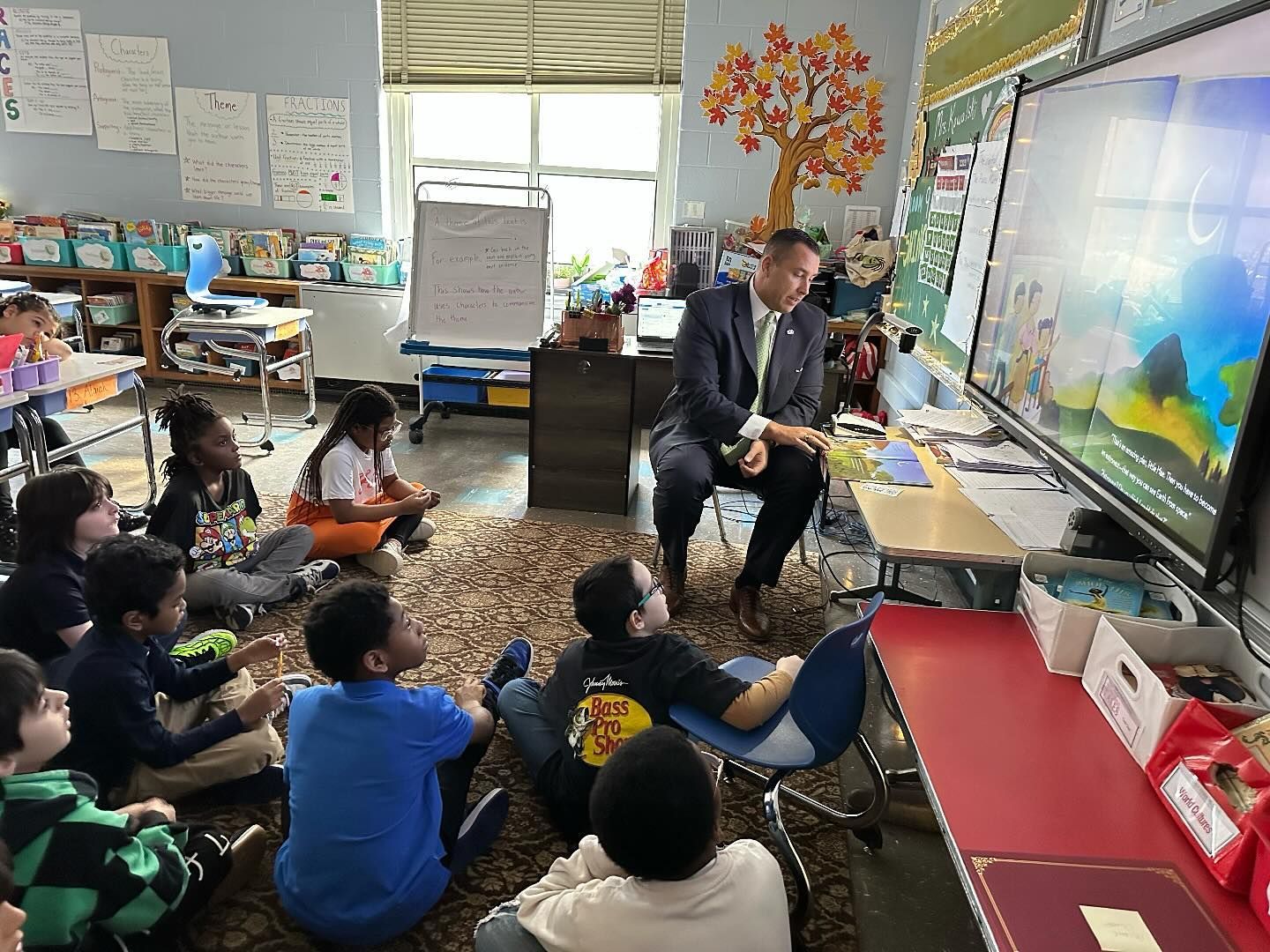 Mike reading in front of a group of children in a classroom.