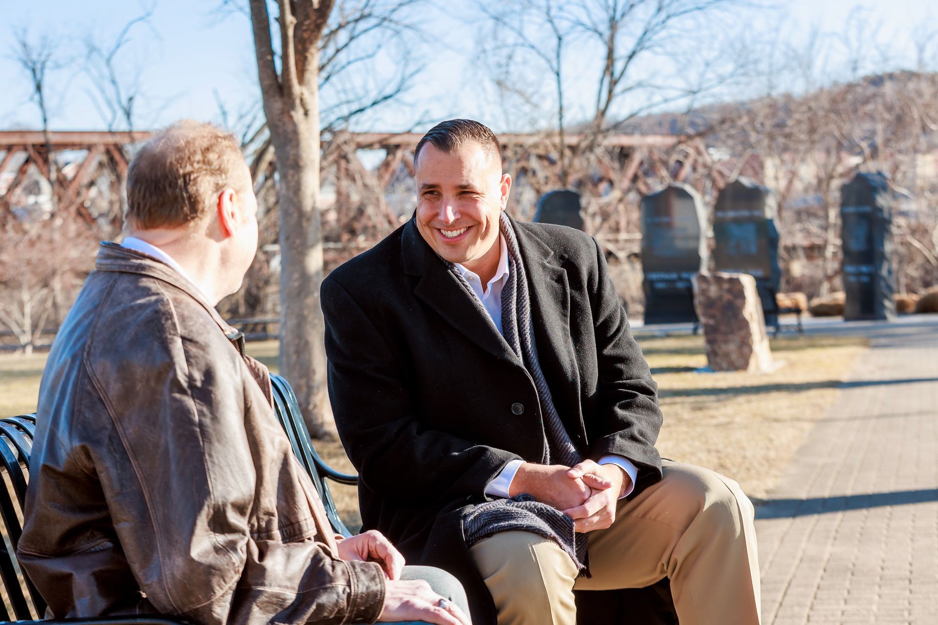 Mike and a Shelton resident are sitting on a bench talking to each other.