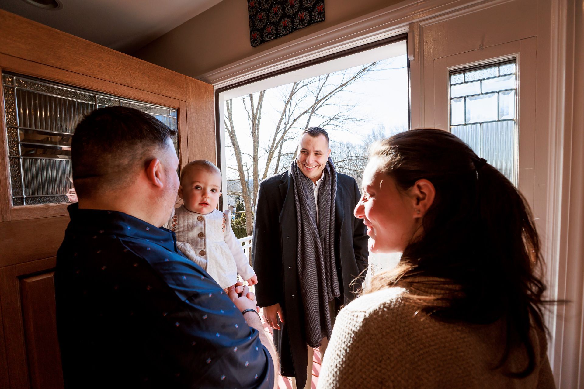 Mike and Shelton family are standing in front of a door talking to each other.