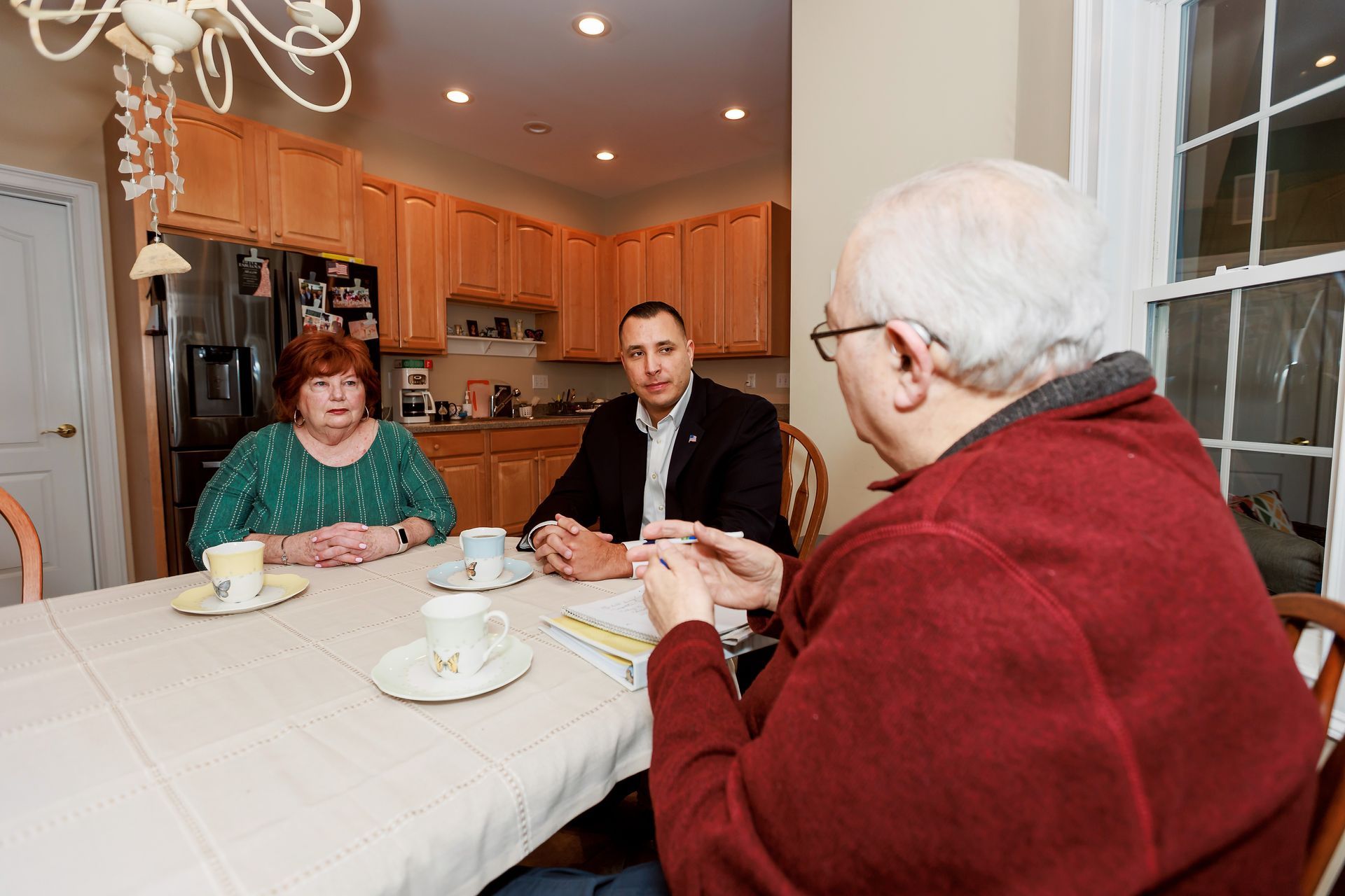 Mike and Shelton residents are sitting at a table in a kitchen having a conversation.