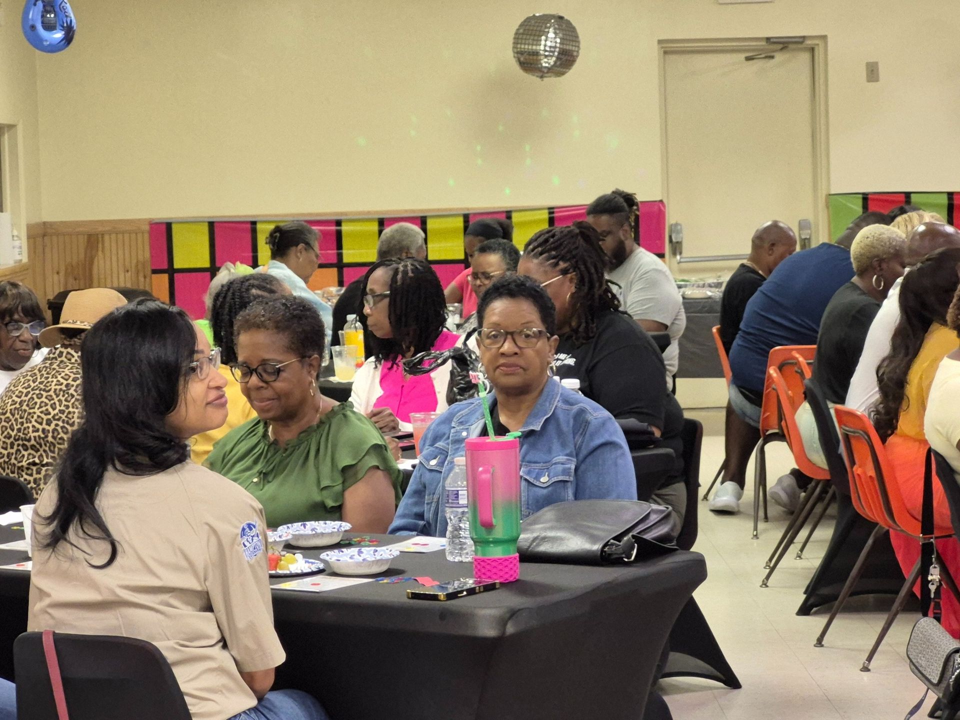 People seated at tables in a room, attending an event.