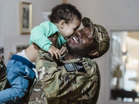 A man in a military uniform is holding a baby in his arms.