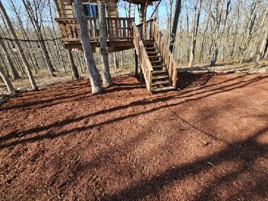 Wooden treehouse with stairs in a leaf-covered forest clearing