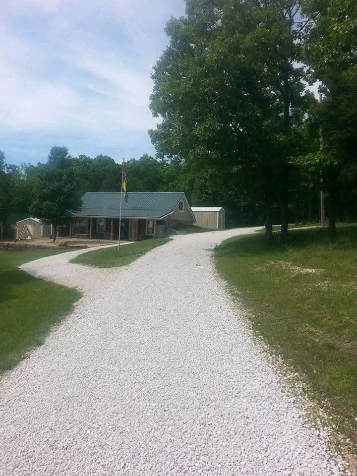 Gravel path leading to a small building and trees on a sunny day