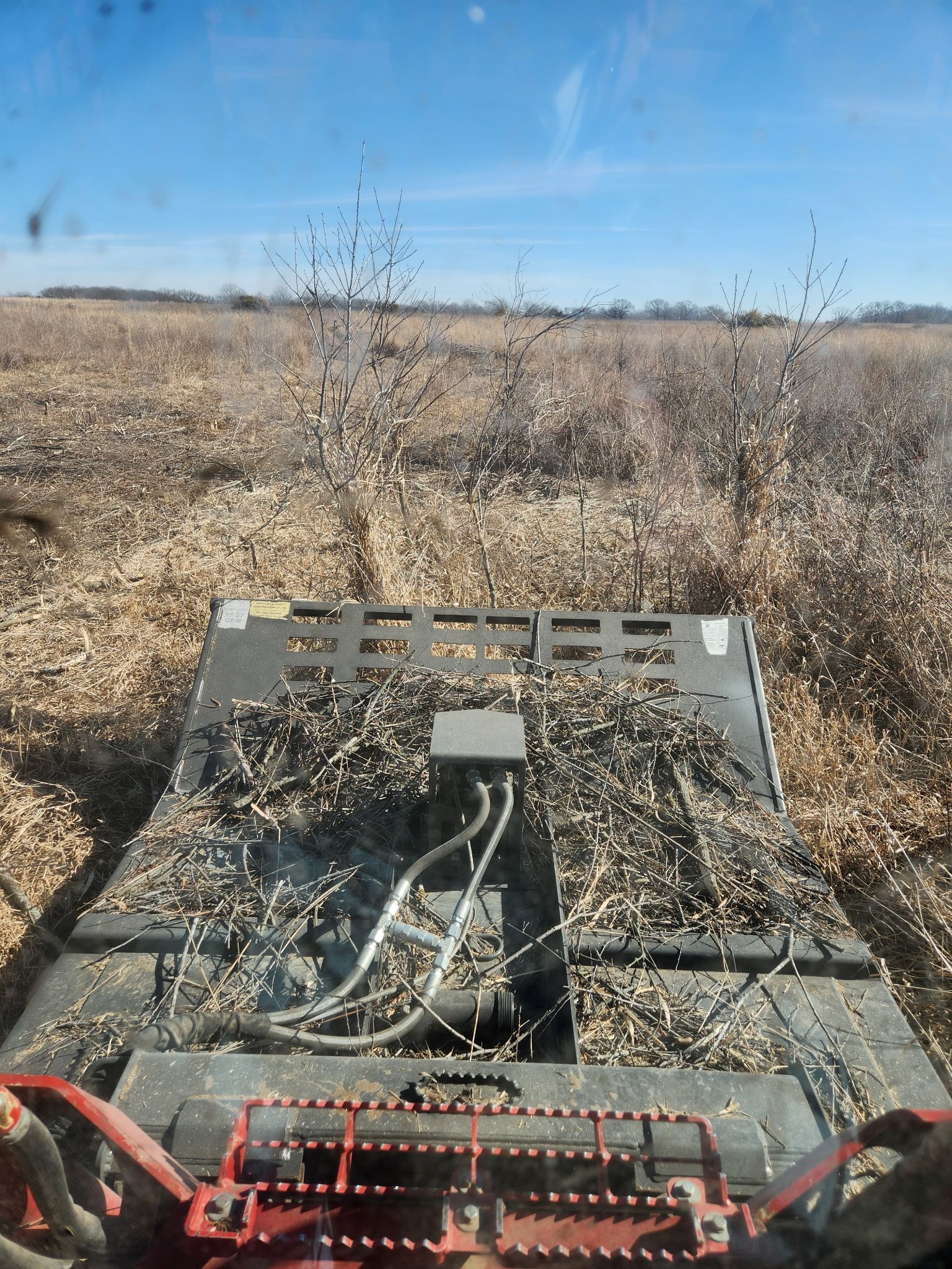 Farming equipment in a dry field under a clear blue sky with weeds in the foreground