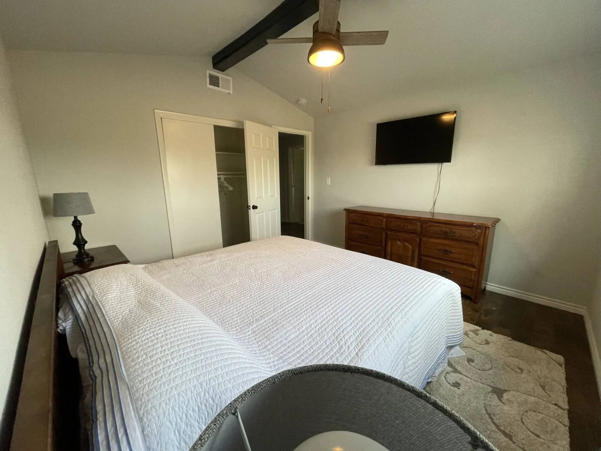 a bedroom with a bed , dresser , lamp and television .