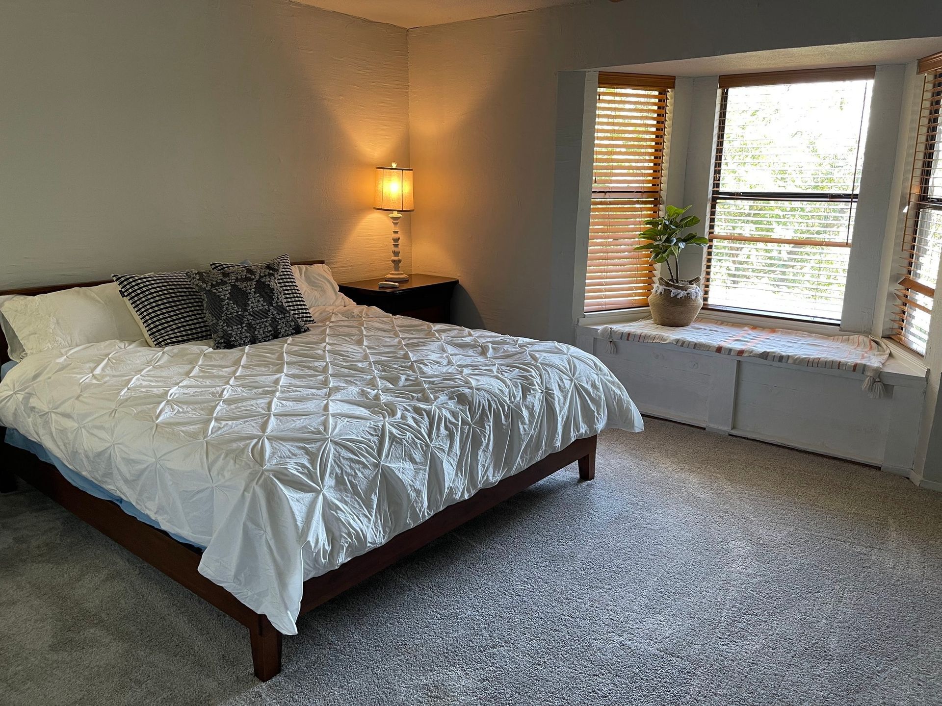 a bedroom with a bed , window seat and lamp .