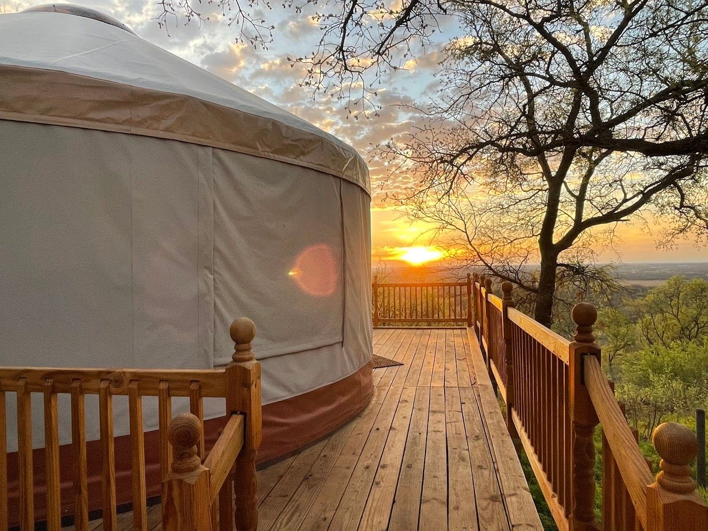 a yurt is sitting on top of a wooden deck at sunset .