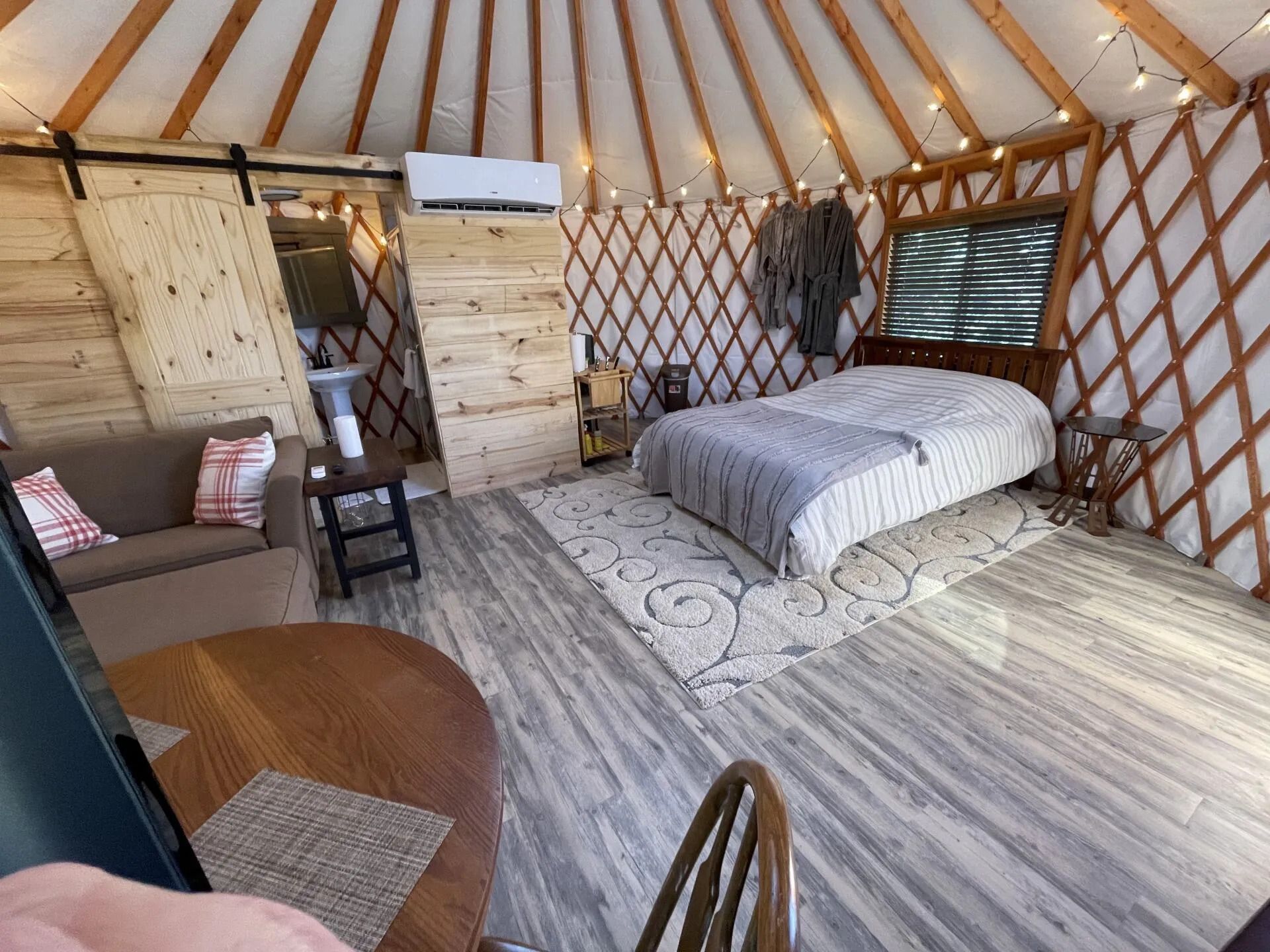 the inside of a yurt with a bed , couch , table and chairs .