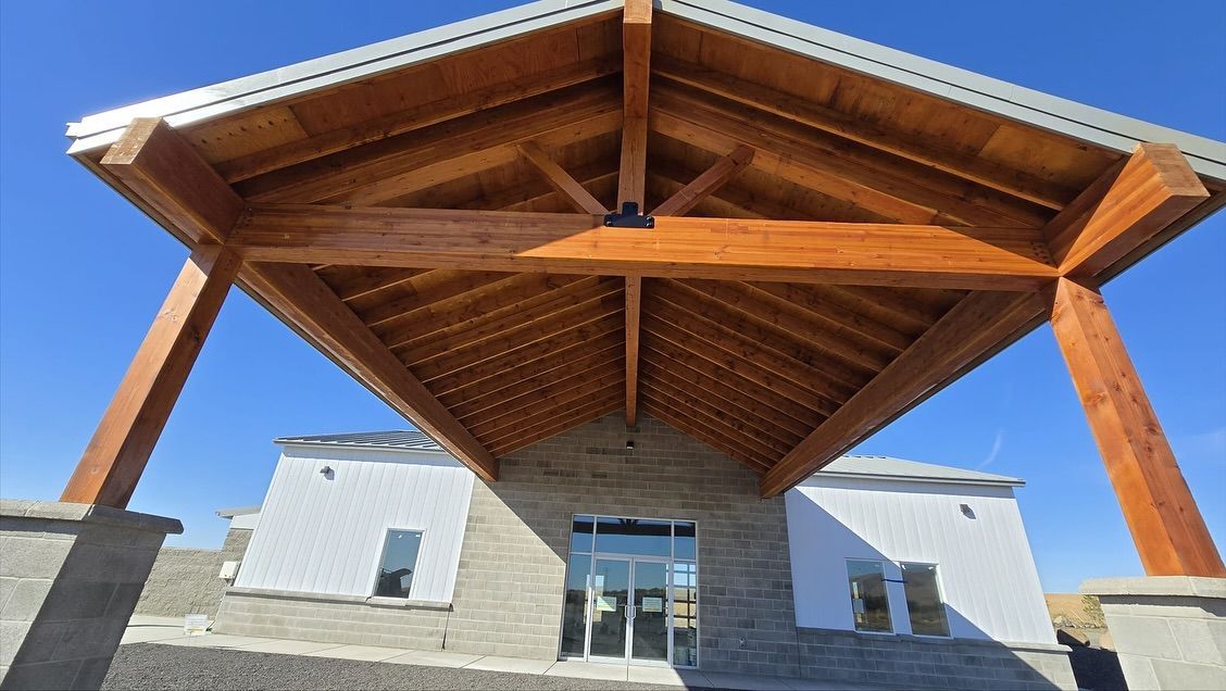 Wooden canopy over a building entrance with a clear blue sky.