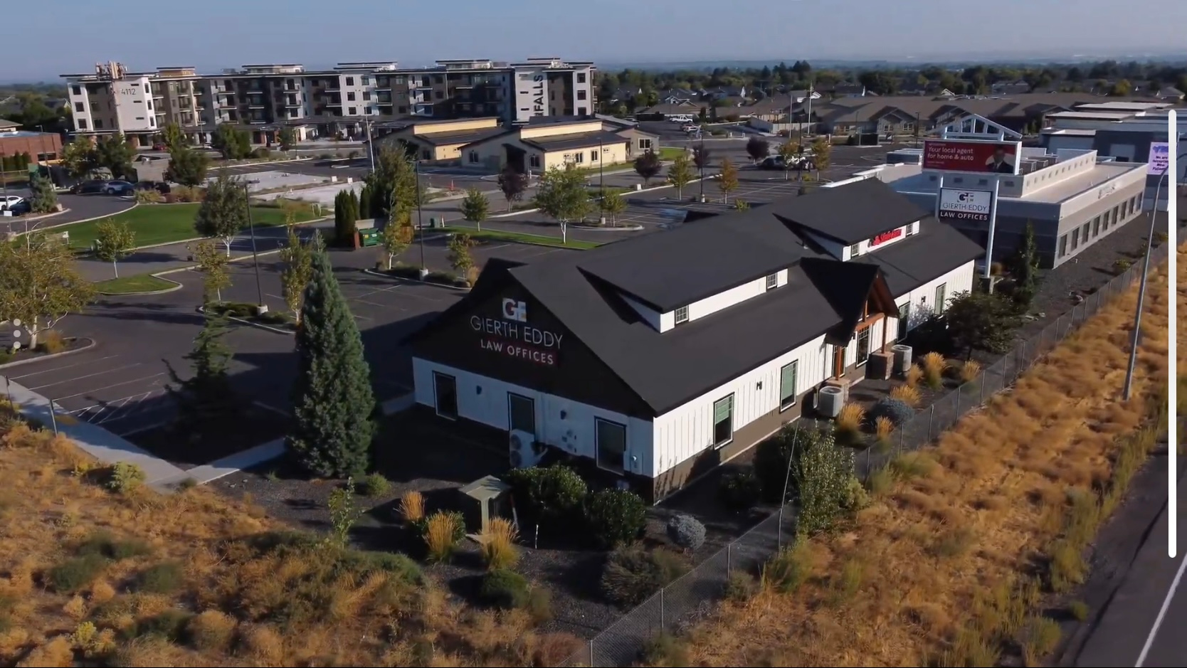 Apartment building under construction; vehicles and portable toilets in the foreground, cloudy sky above.