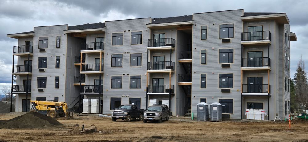 Construction site with a four-story apartment building under construction, cloudy sky above.