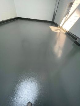 Gray, shiny floor with a white spill. The room has white walls, sunlight, and a dark border.