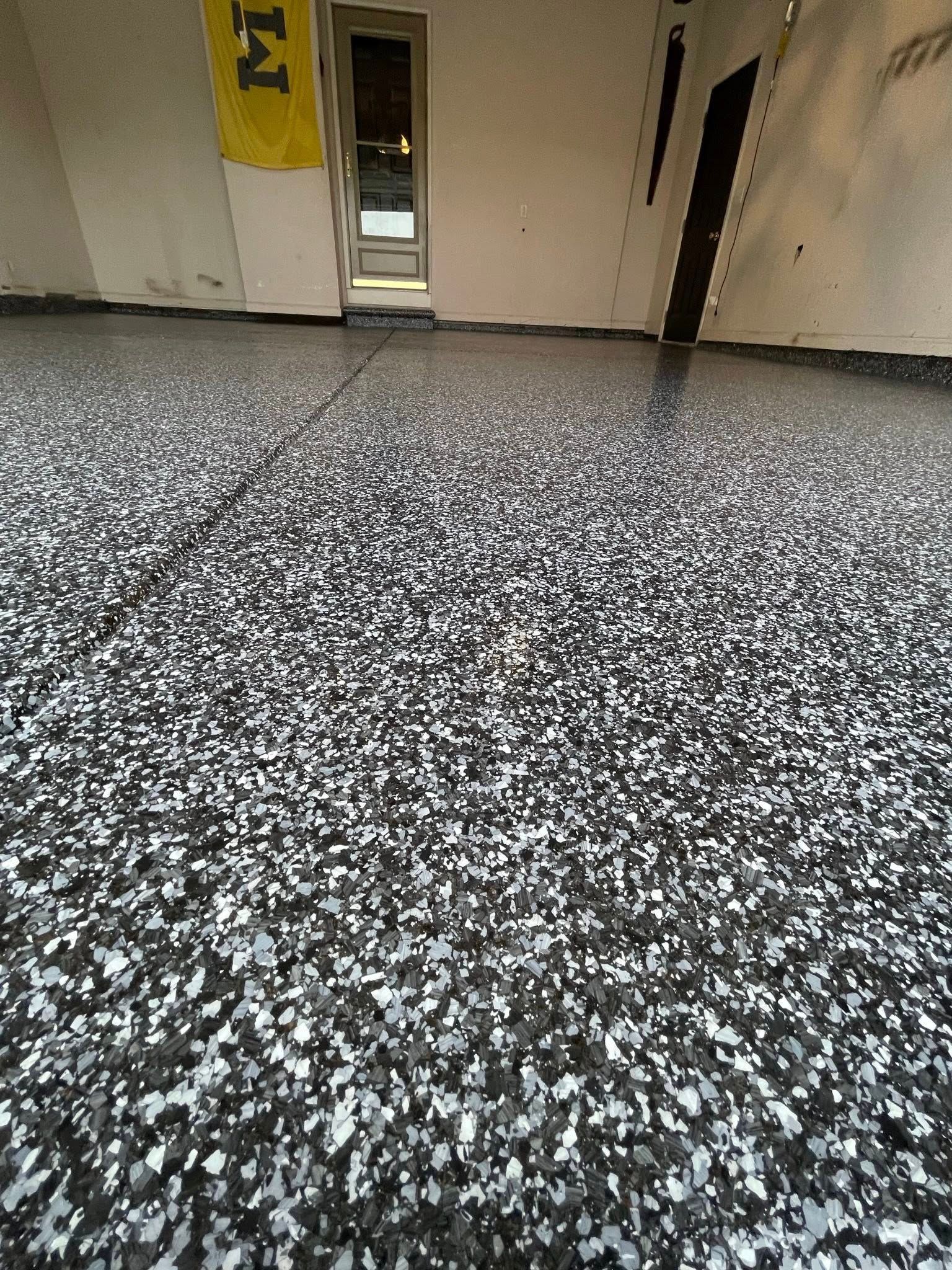 Garage floor with a speckled epoxy coating in shades of gray and white.
