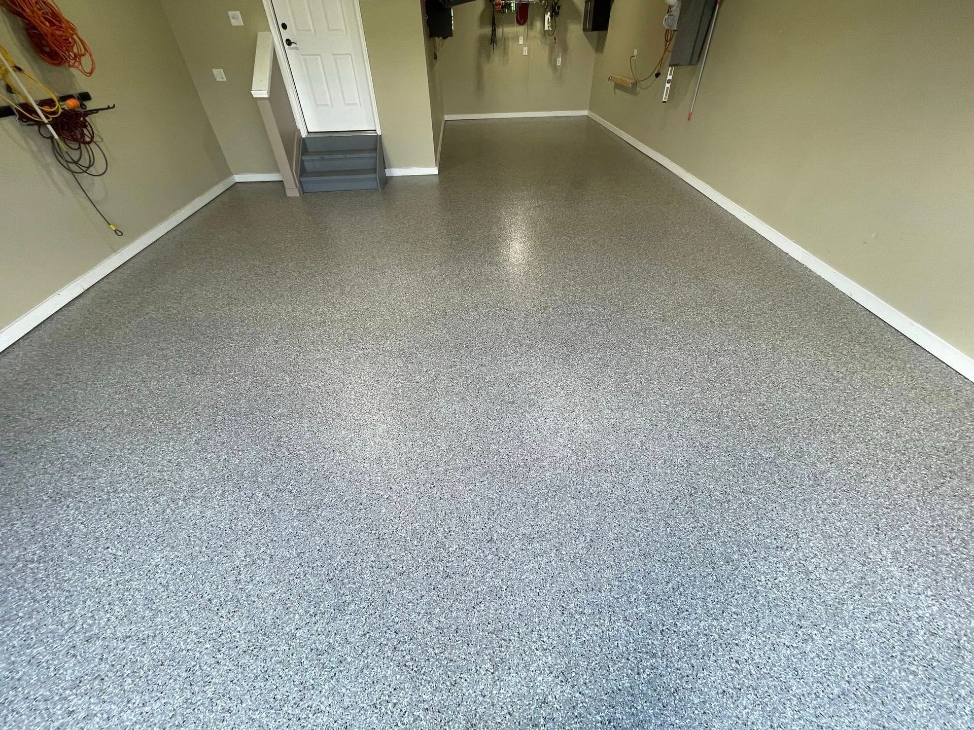 Garage floor with a speckled gray epoxy coating.