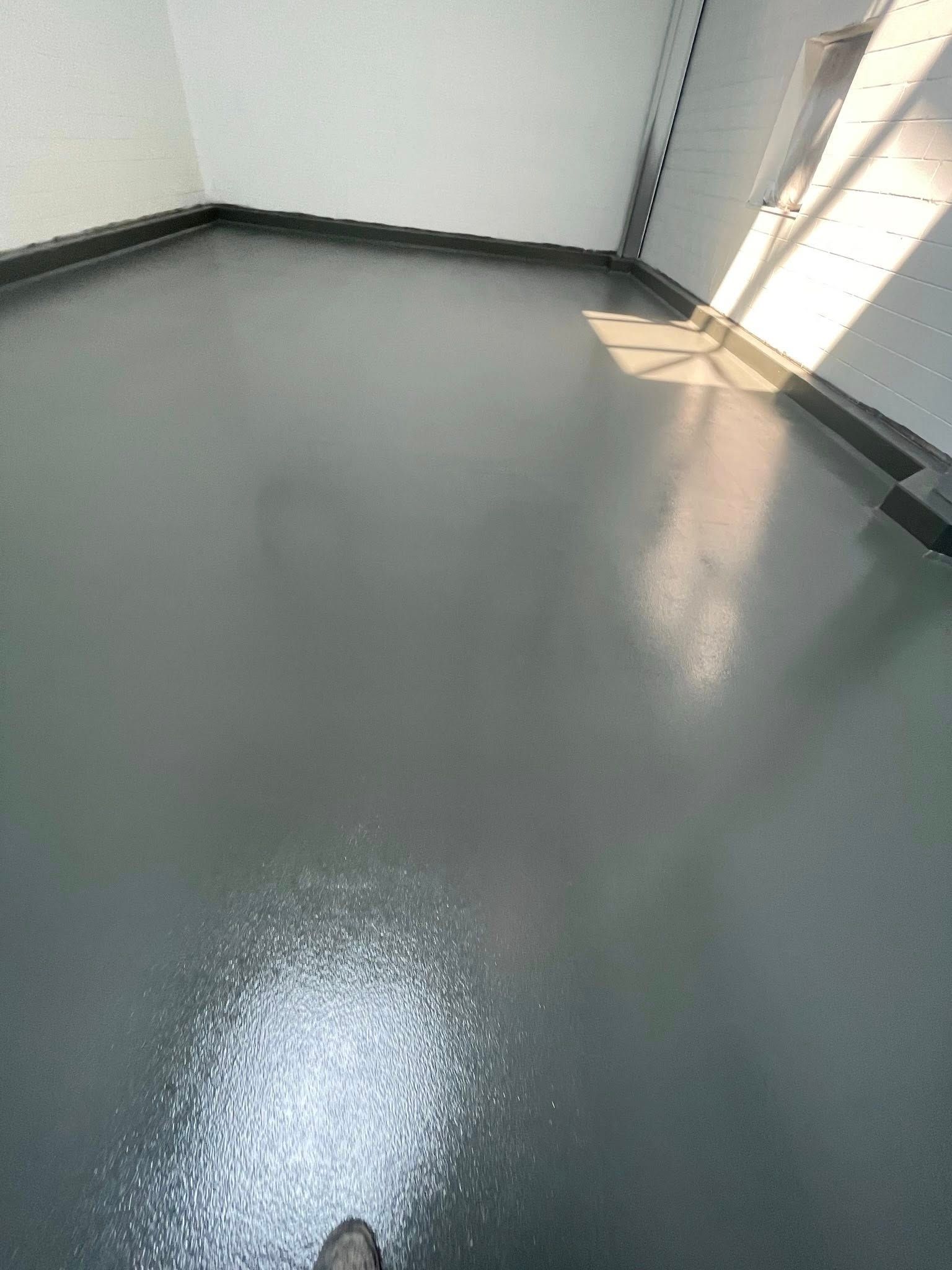 Gray, reflective floor with white substance scattered. Light streams through a window.