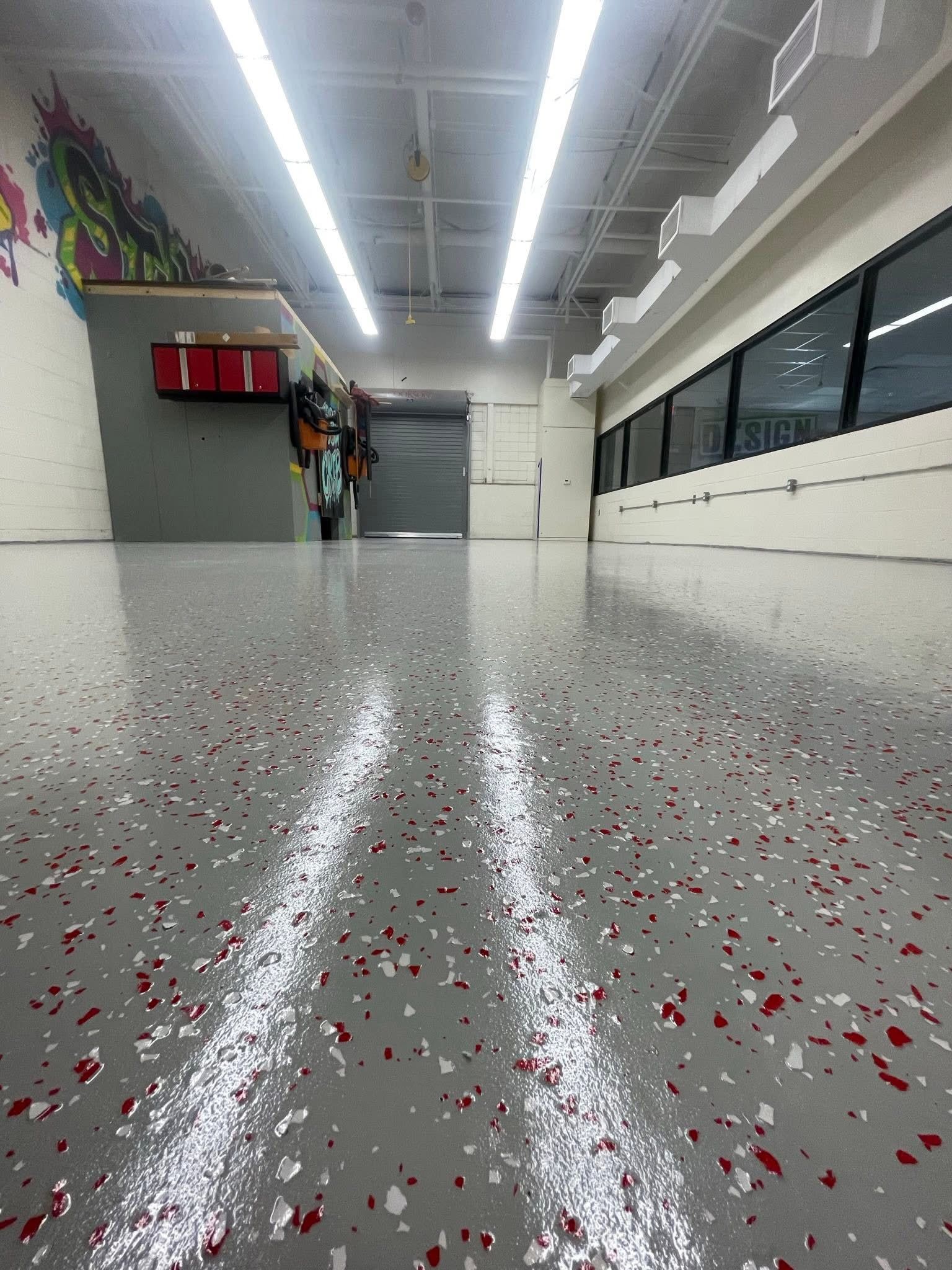 A wide shot of a shiny, speckled grey floor in a bright room, with windows and equipment visible.