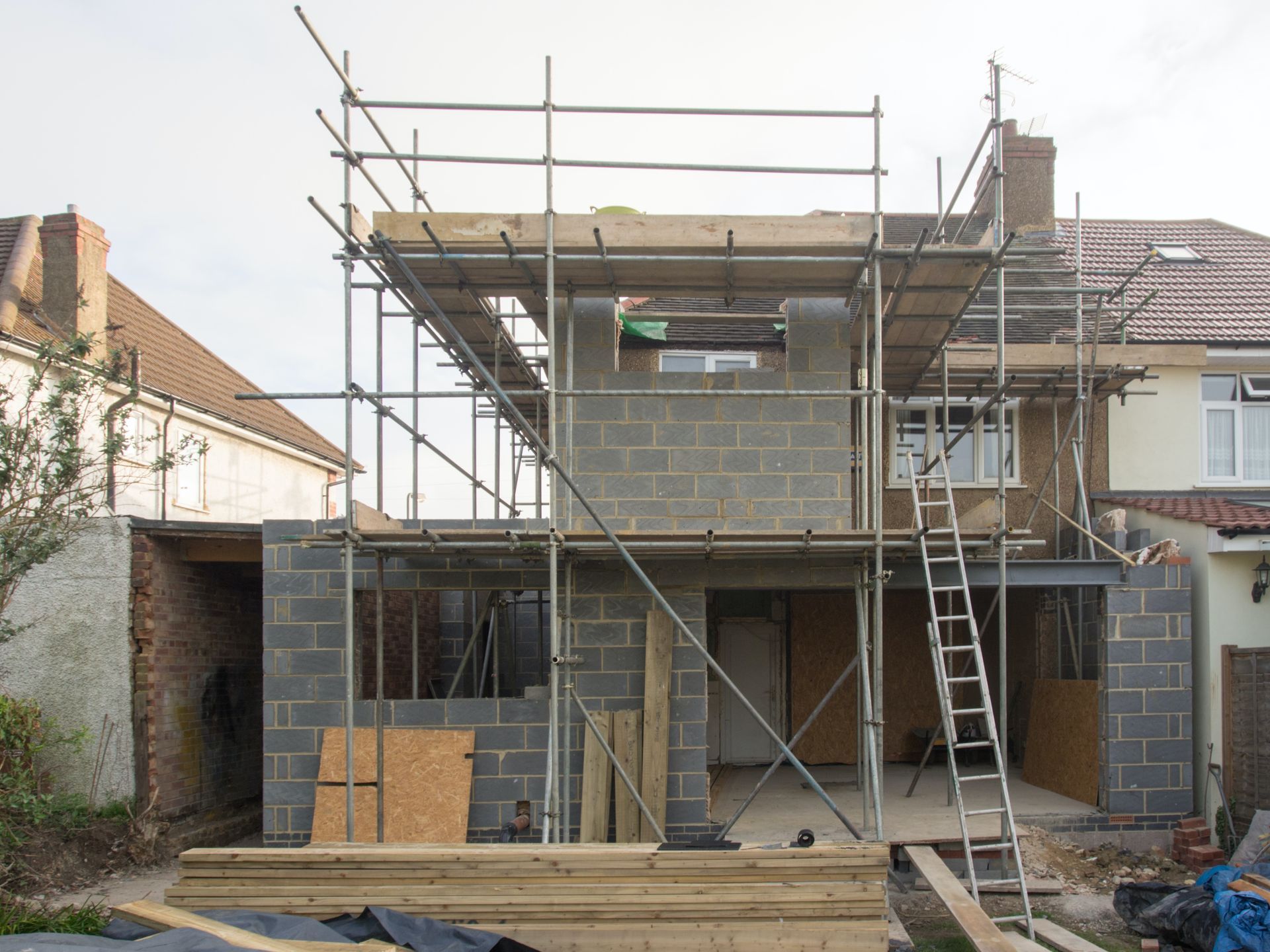 a building under construction with scaffolding and a ladder