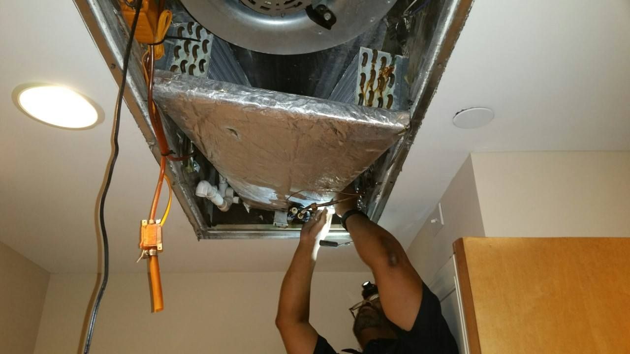 A man is working on a ceiling fan in a room.