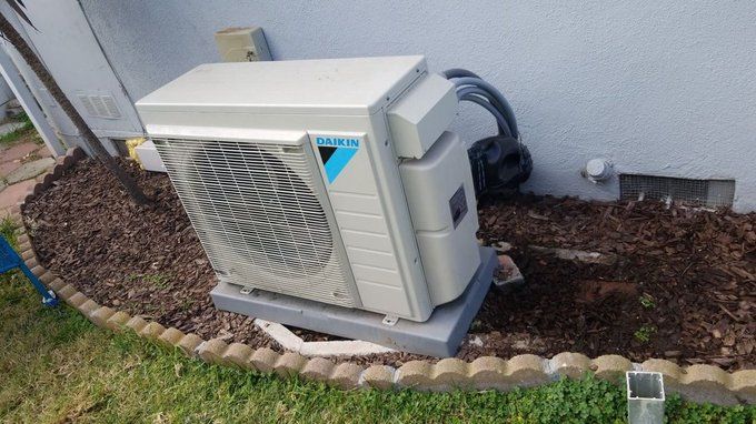 A white air conditioner is sitting on the side of a house.