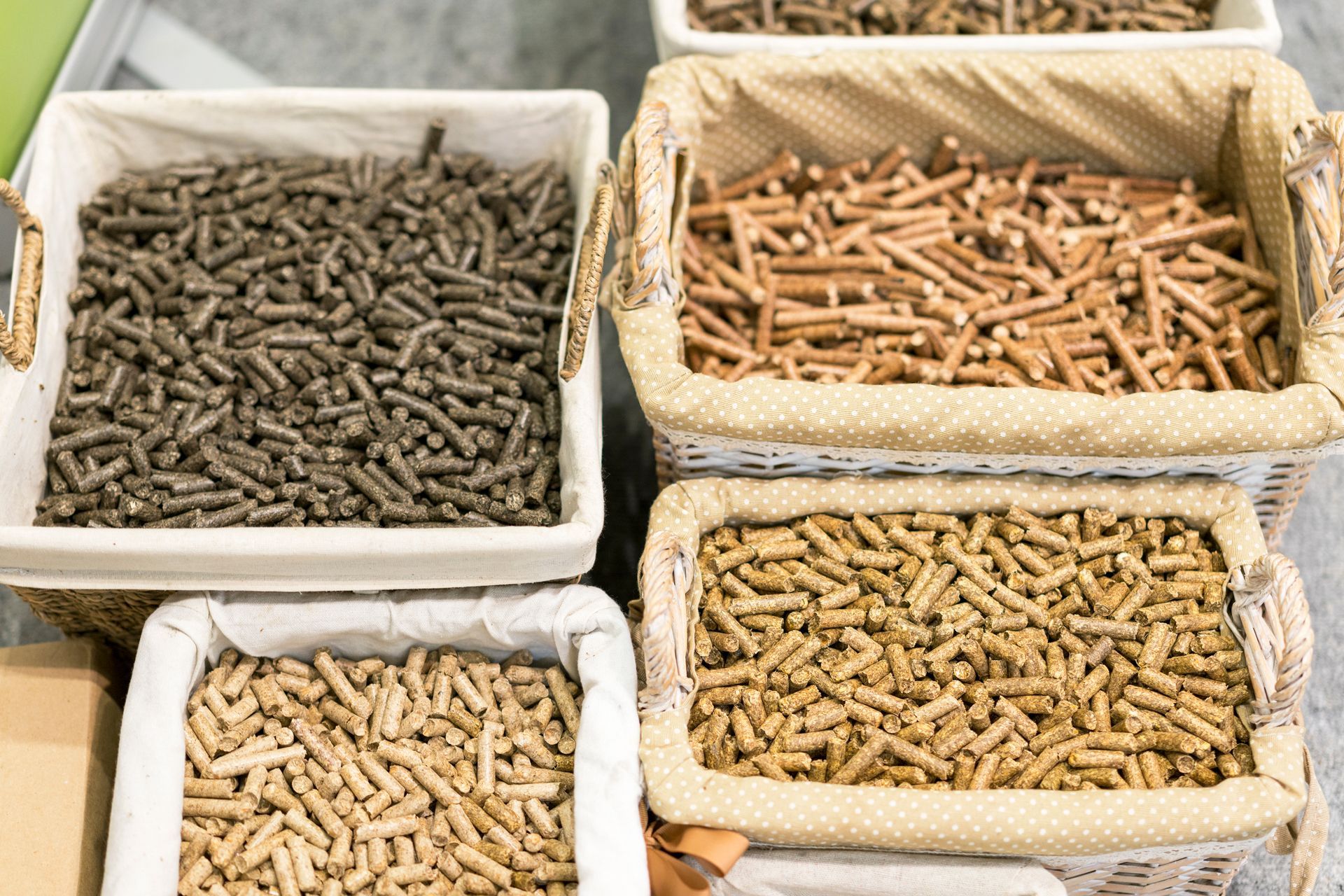 Four baskets of wood pellets, varying in color from brown to tan, for use as fuel