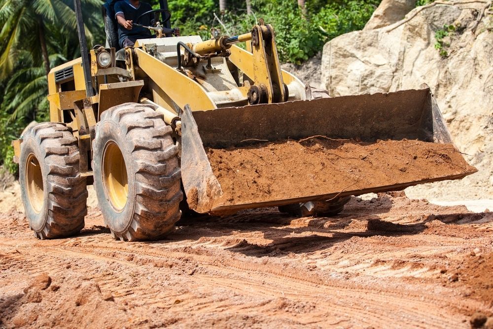 A Bulldozer is Moving Dirt on a Dirt Road — Diggamen Civil Contracting in Tivendale, NT