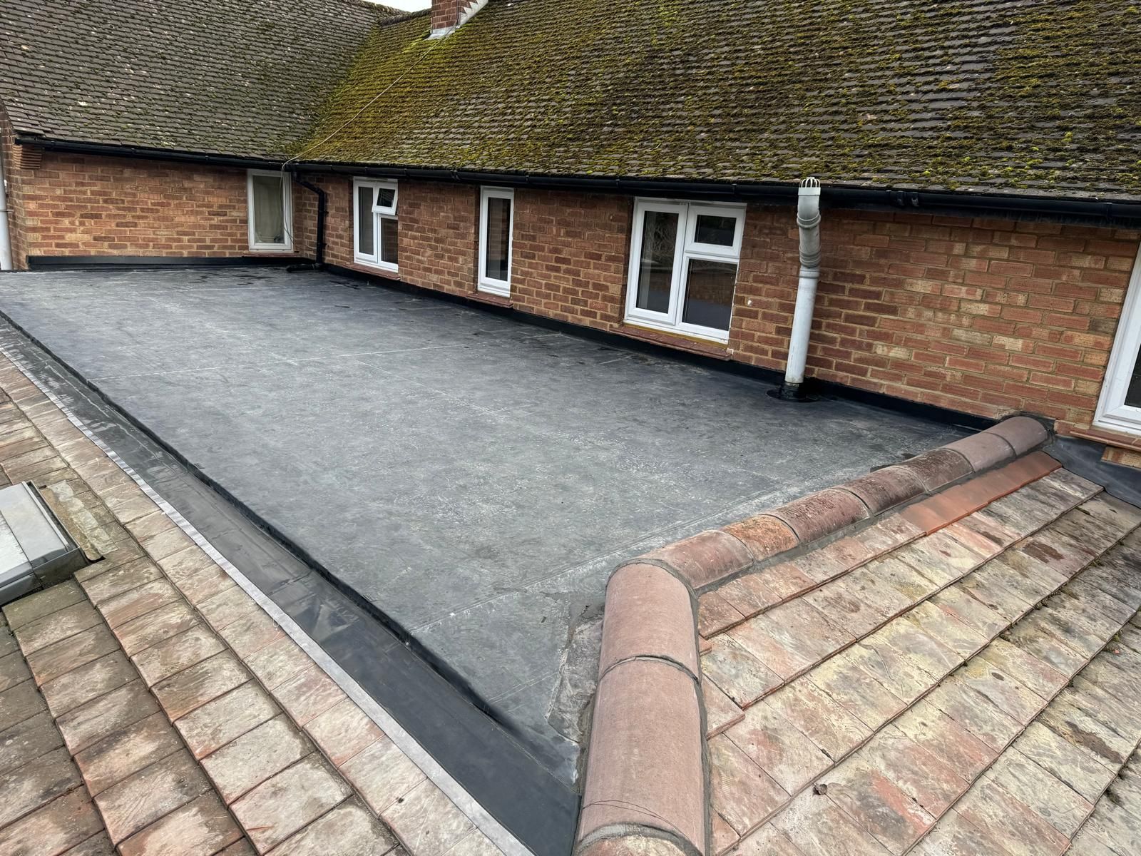 A brick building with a flat roof and a drain on the side of it.