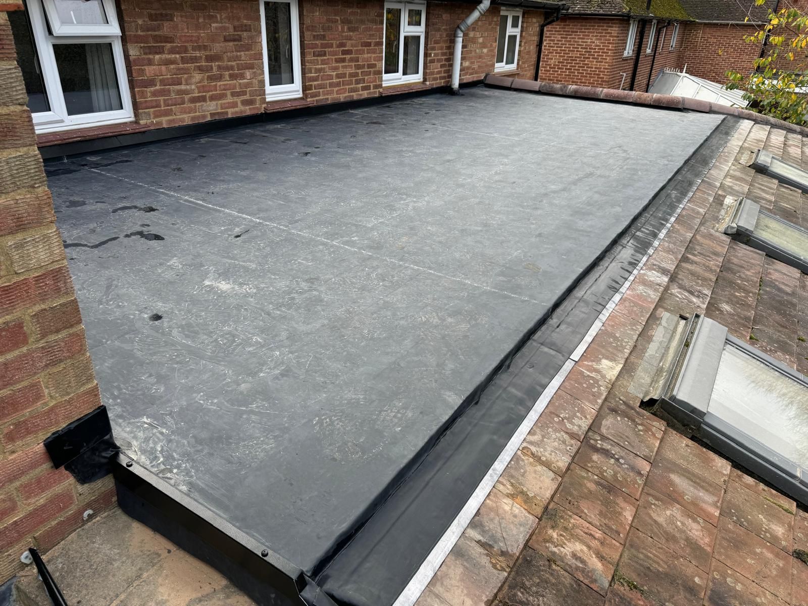 A roof with a black roof and a brick building in the background.
