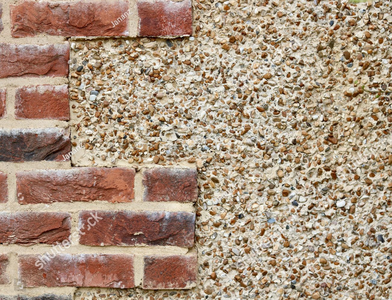 A close up of a brick wall next to a gravel wall.