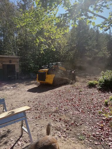 A yellow bulldozer is moving dirt in a yard.